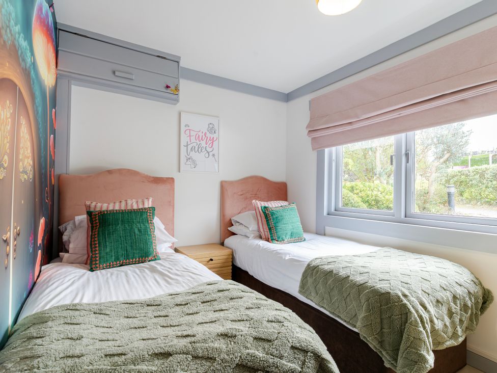 A bedroom with two beds and a fairy tale picture at Kinder Lodge 3 Spa (Pet) Redruth