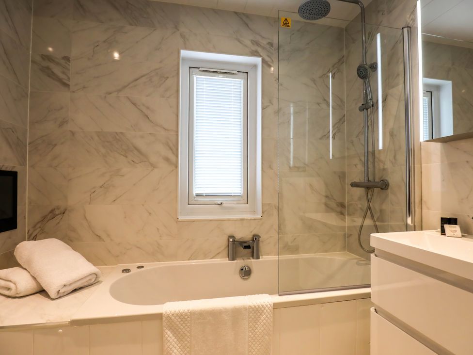 A bathroom with a bathtub and shower at Signature Lodge 4 in Redruth