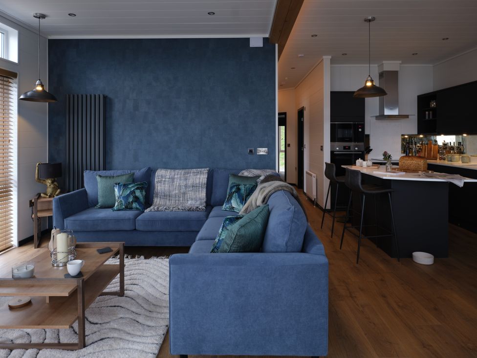 A living room with a sofa, coffee table and kitchen island at Wilde Spa (Pet) Carmarthen