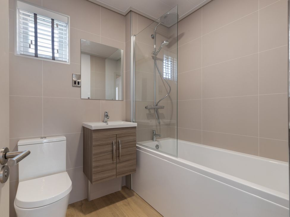 A bathroom with a toilet, bathtub, shower, and mirror at Wilde Spa (Pet) in Carmarthen