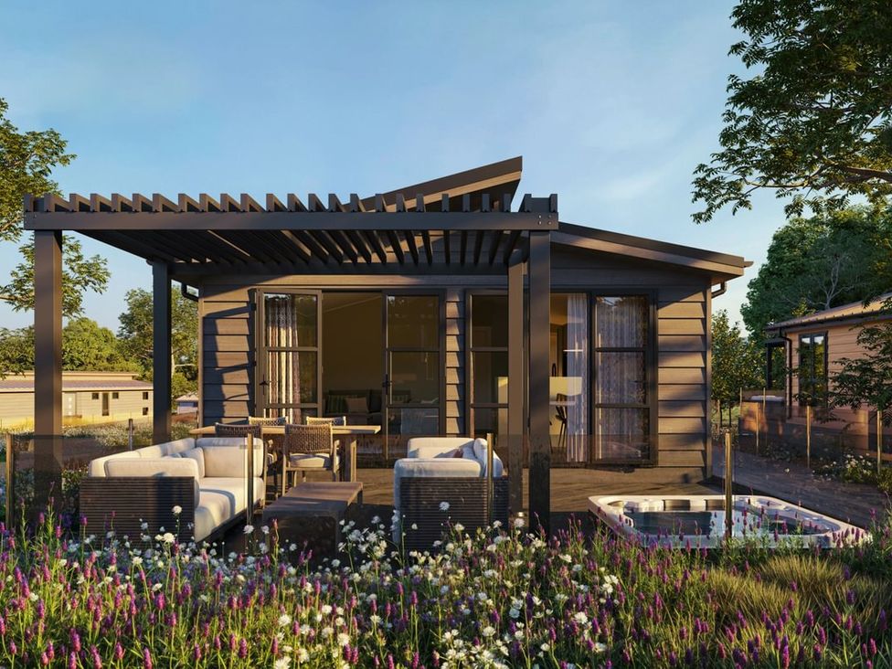 A cabin with outdoor seating and flower beds at Hesk (Pet) Penrith