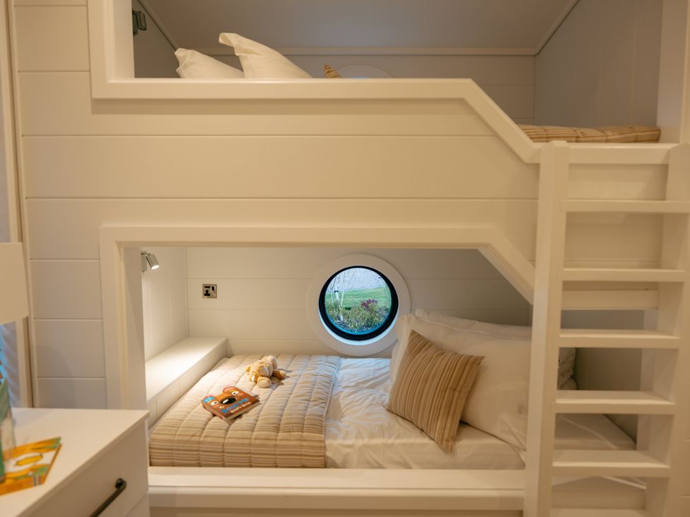 A bedroom with bunk beds and a round window at Wansfell (Pet) Penrith