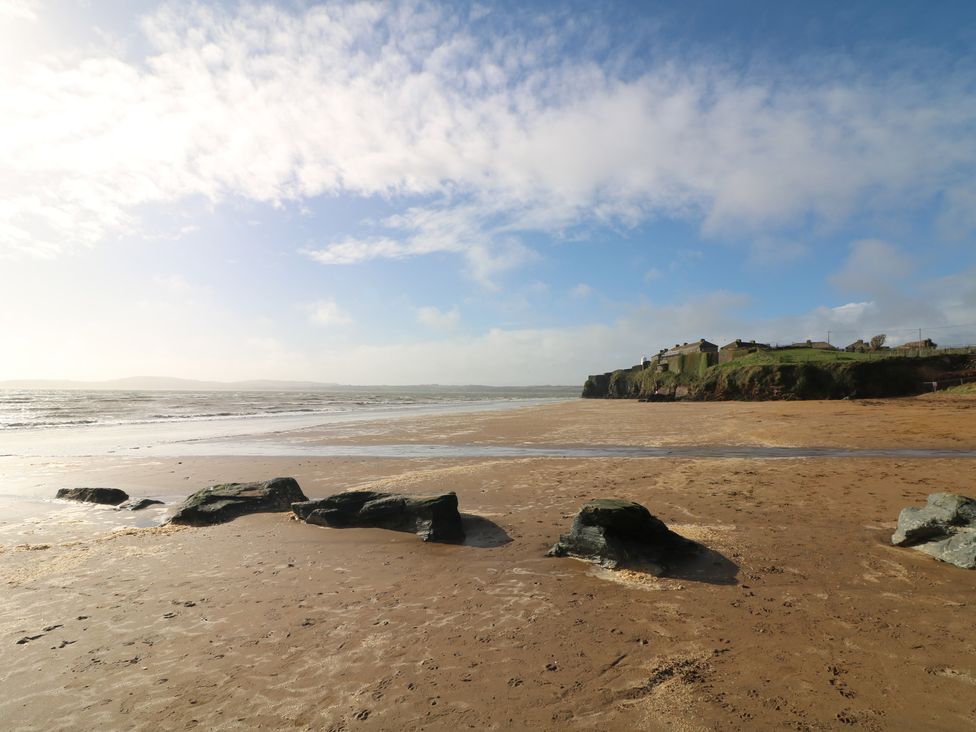 A beach with rock formations and houses on a cliff at Radharc an Hook @ Estuary Bliss