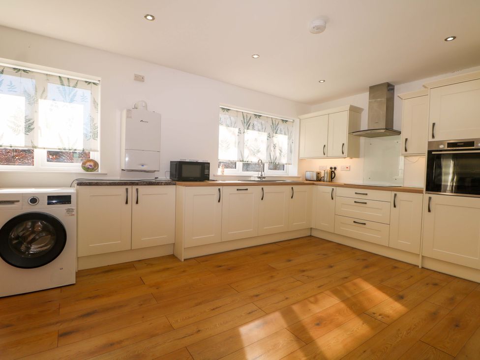 A kitchen with a washing machine and microwave at Blue Bell Cottage near Lenham
