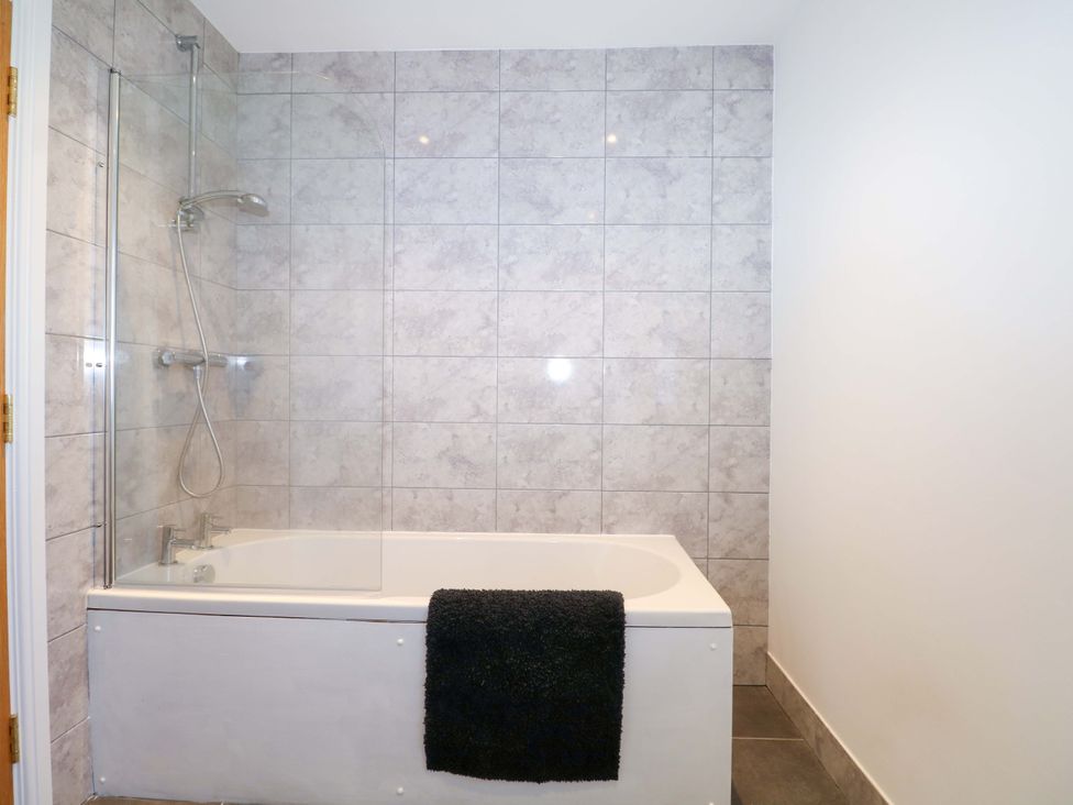 A bathroom with a bathtub and shower at Blue Bell Cottage near Lenham