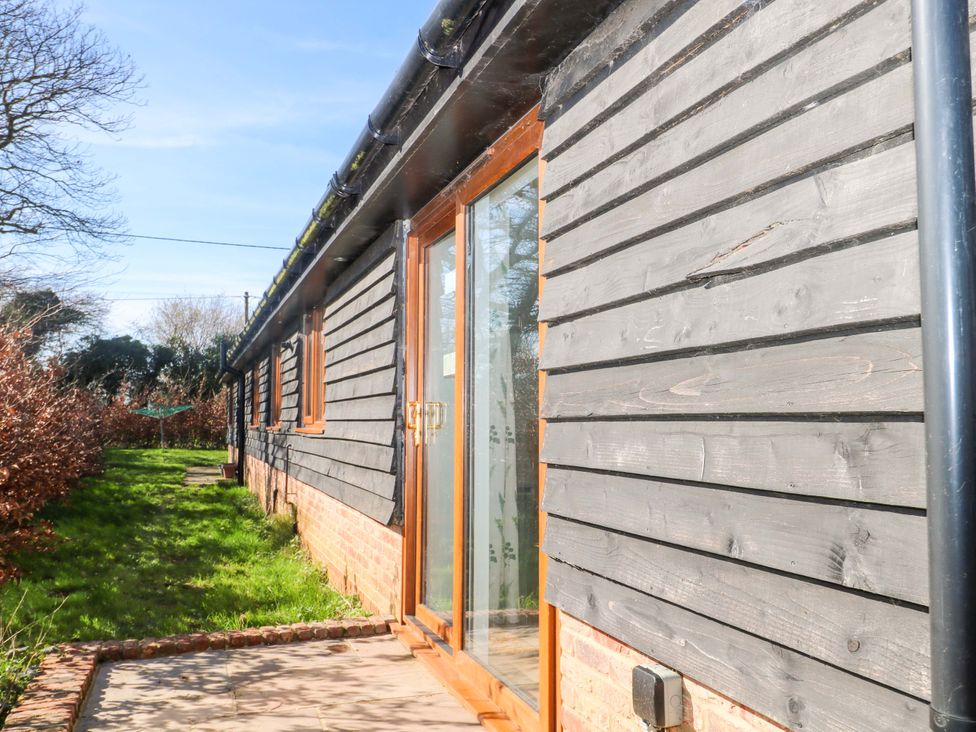 An exterior view of a building with a door and grass at Blue Bell Cottage near Lenham