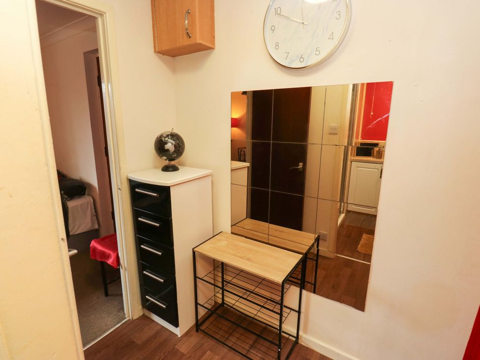 A hallway with a mirror, a clock, and furniture at Cosy Nook in Leeds