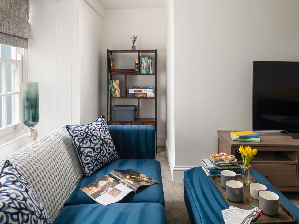 A living room with a blue sofa and bookshelves at Tides Door in Dartmouth