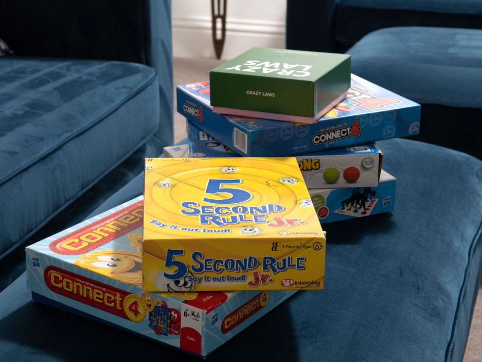 A stack of board games on a couch at Tides Door in Dartmouth