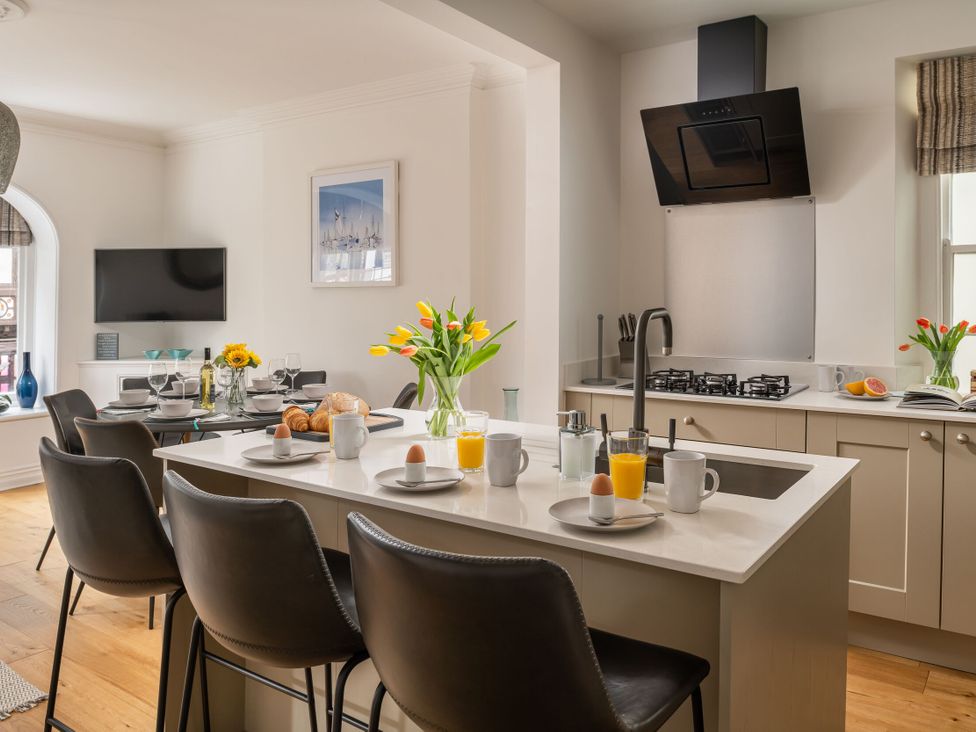 A kitchen with a dining table and flowers at Tides Door in Dartmouth