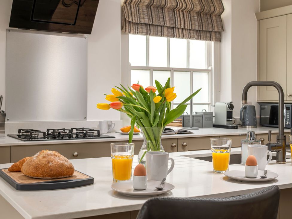 A kitchen with a gas stove and flowers on the counter at Tides Door in Dartmouth