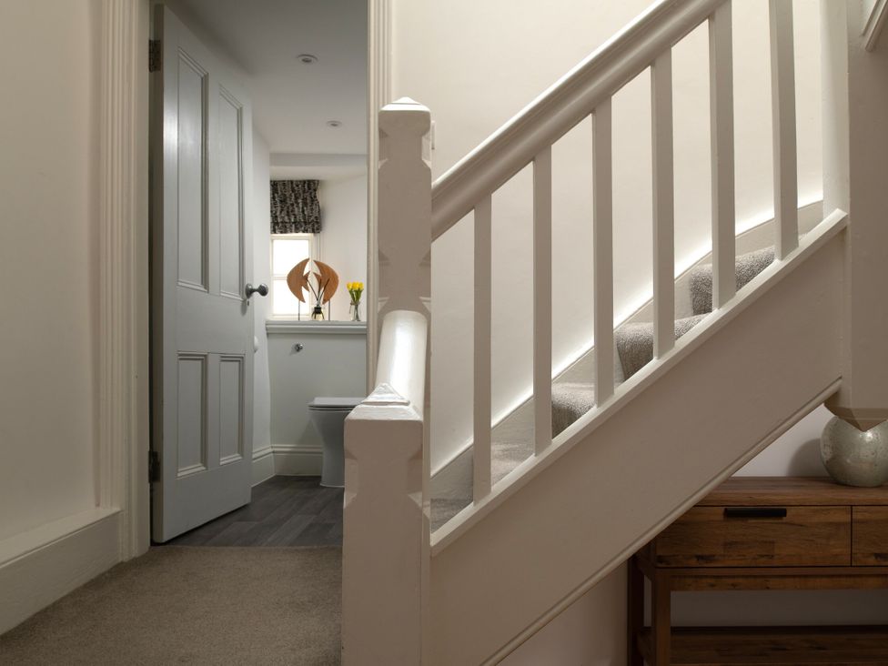 A hallway with a staircase and a wooden console table at Tides Door in Dartmouth