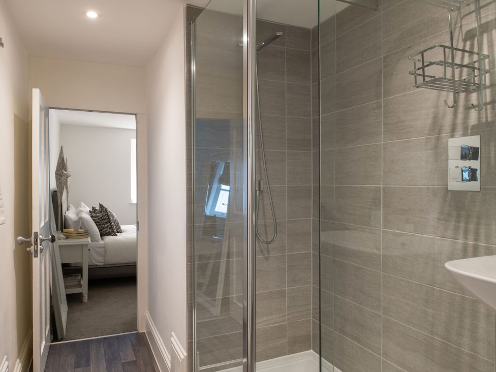 A bathroom with a shower and a view of a bedroom at Tides Door in Dartmouth