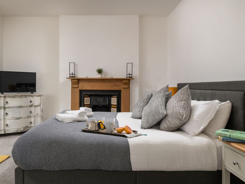 A bedroom with a bed, television, and fireplace at Tides Door in Dartmouth