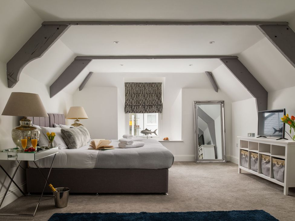 A bedroom with a bed, lamp, mirror, and television at Tides Door in Dartmouth