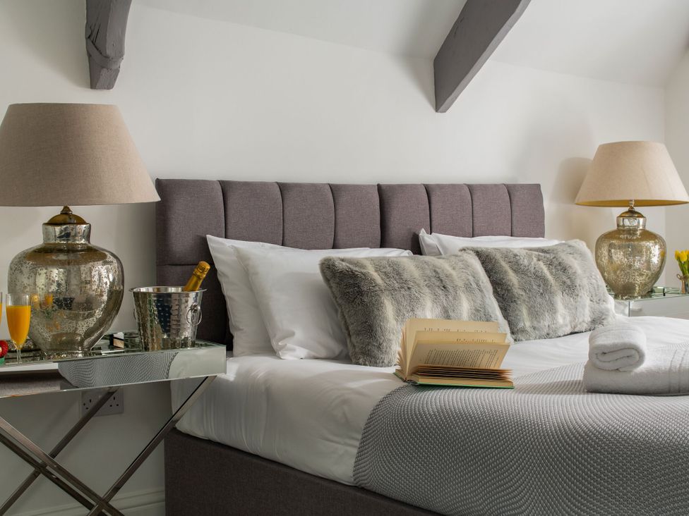 A bedroom with a bed, lamps, and decorative items at Tides Door in Dartmouth