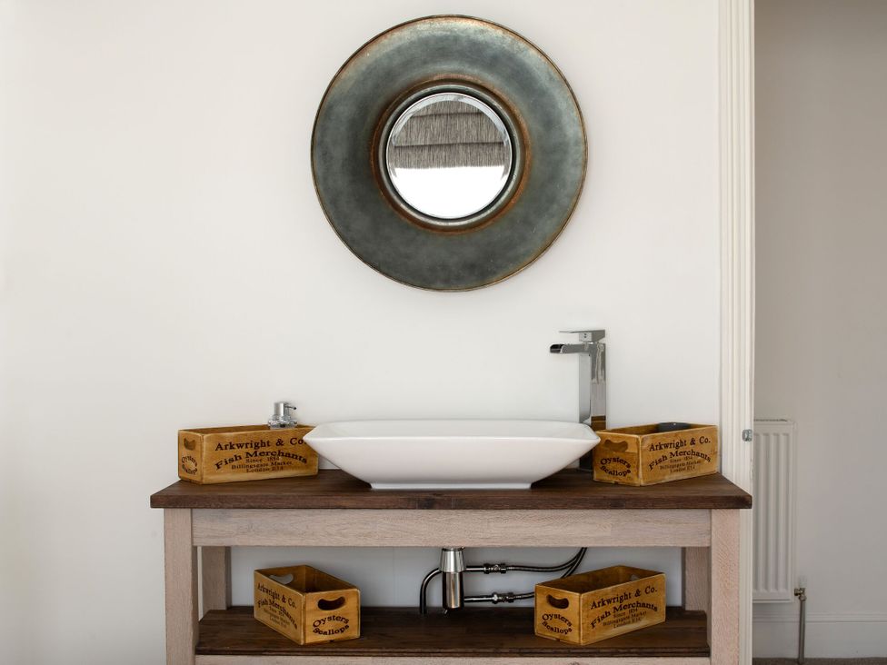 A sink with a mirror and wooden boxes in a bathroom at Tides Door in Dartmouth
