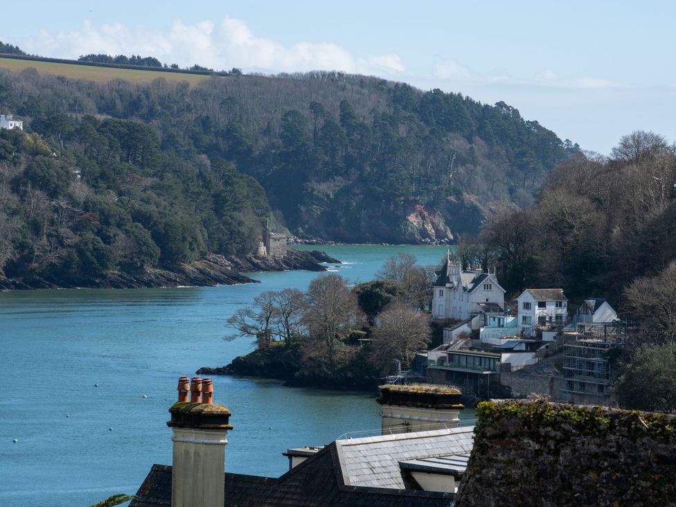 A view of a river with buildings and trees in the background at Tides Door in Dartmouth