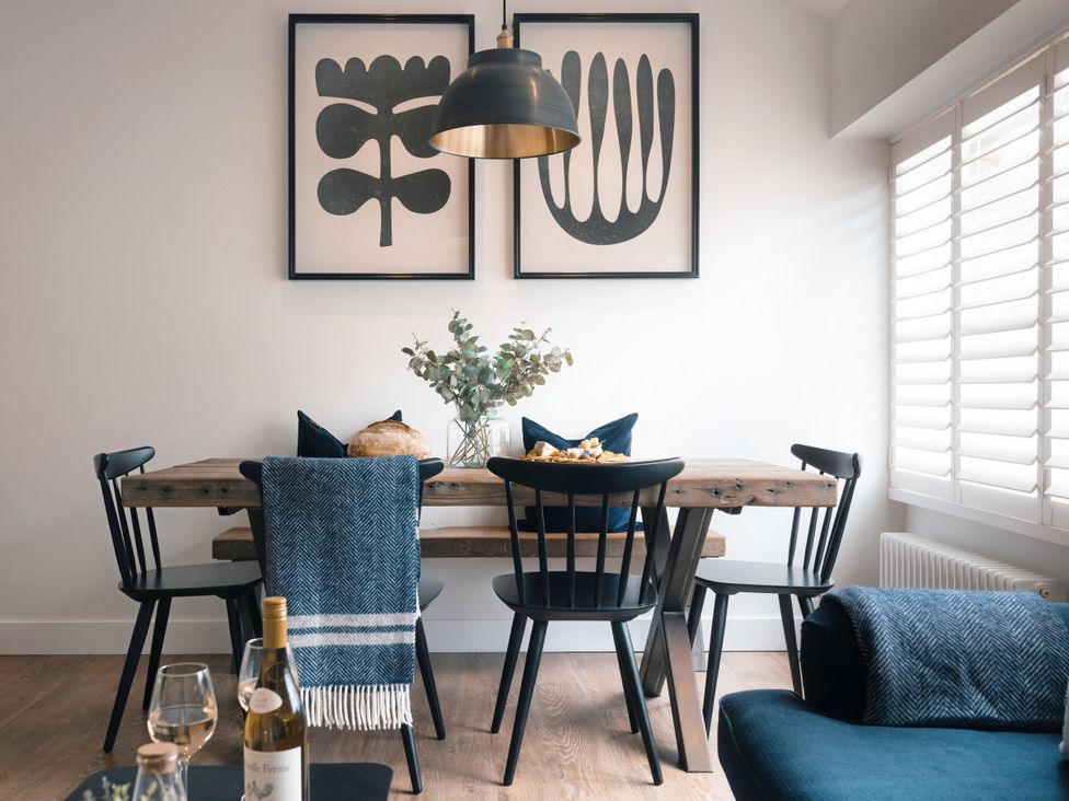 A dining room with a table and black chairs at 28 Piazza, St Ives