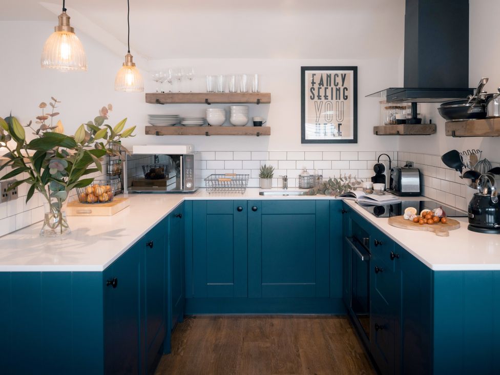 A kitchen with blue cabinets and appliances at 28 Piazza in St Ives