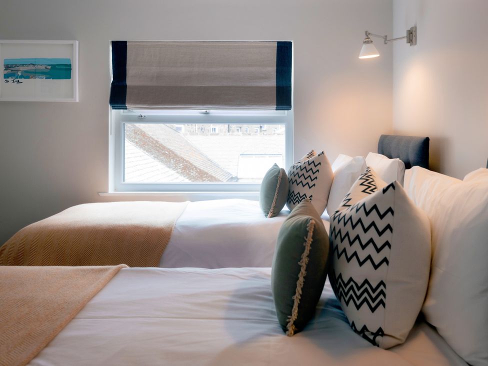 A bedroom with two beds and a window at 28 Piazza St Ives