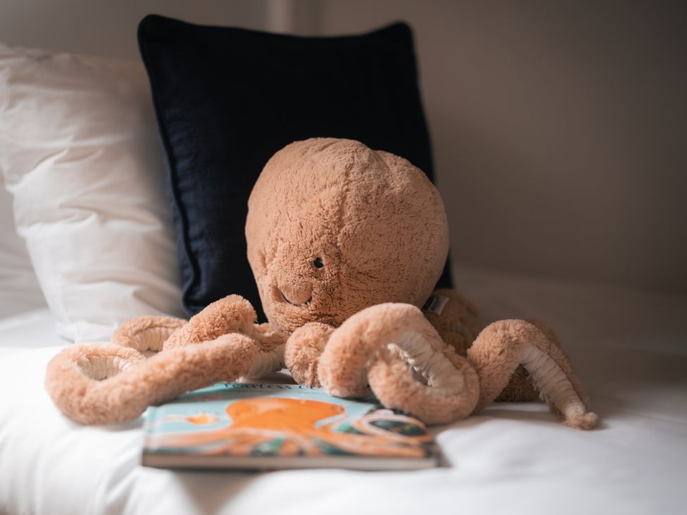 A soft toy octopus and a book on a bed at 28 Piazza St Ives