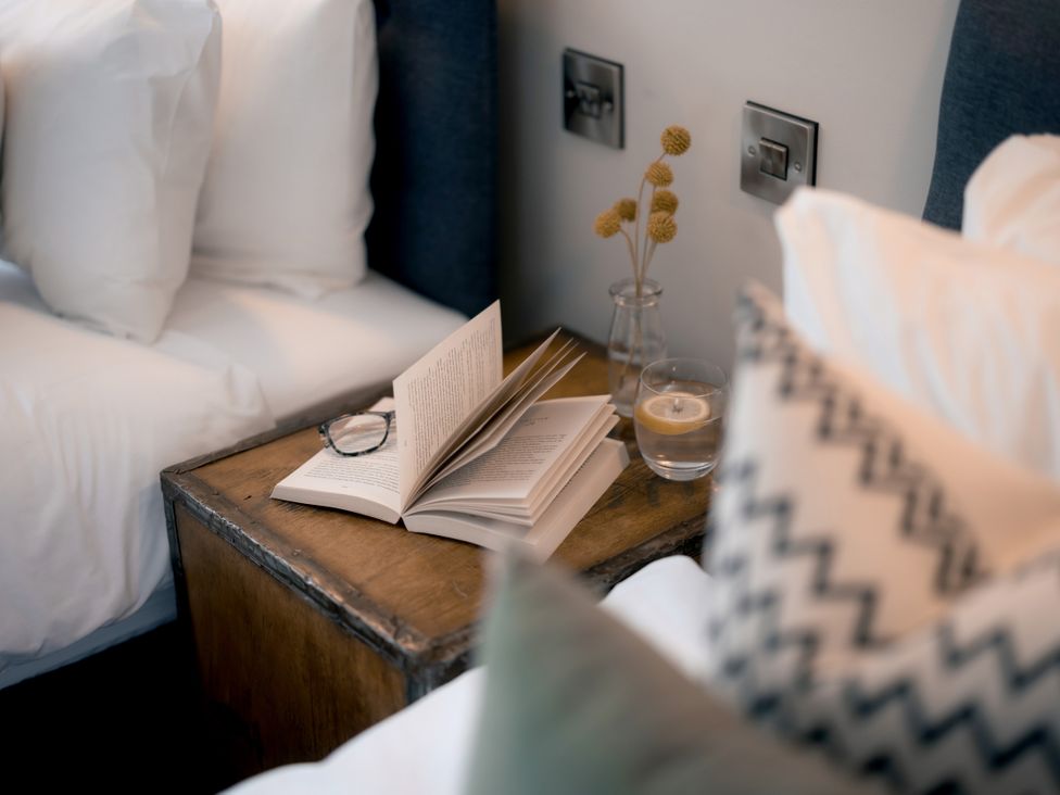 A bedroom with a book and glass of water on a nightstand at 28 Piazza St Ives