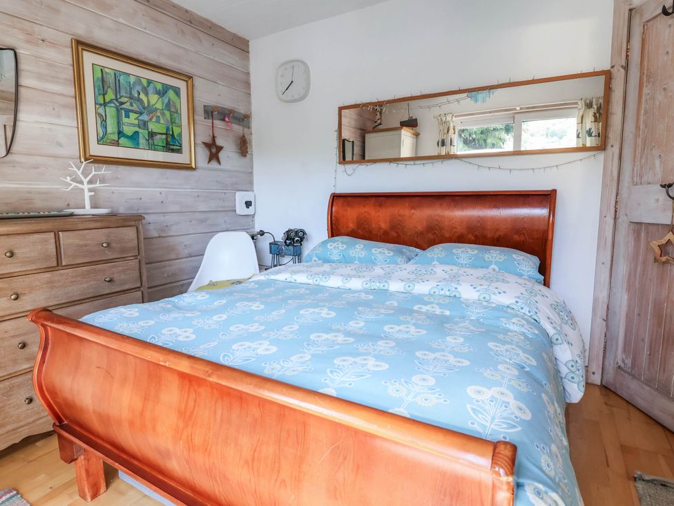 A bedroom with a bed and a dresser at The Boat House in Rudyard Lake