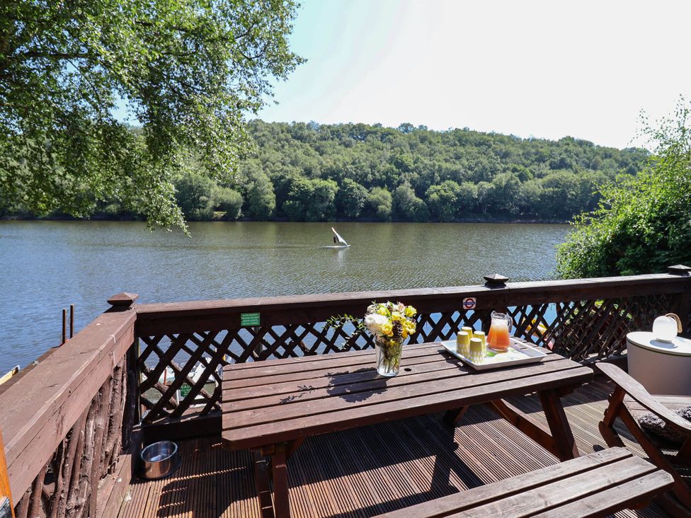 An outdoor area with a table and flowers overlooking a river at The Boat House Rudyard Lake