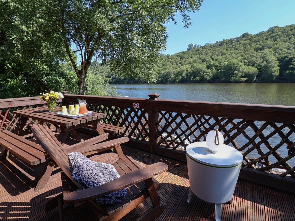 An outdoor area with a table and chairs overlooking a river at The Boat House in Rudyard Lake