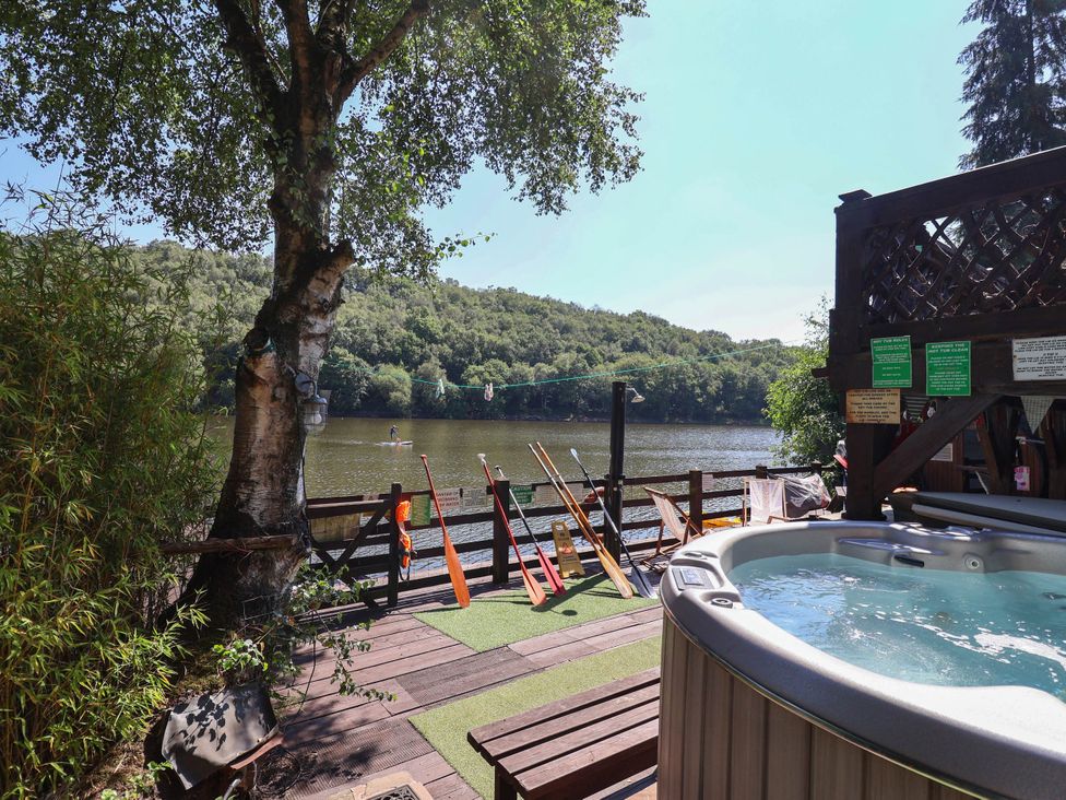 An outdoor area with a hot tub overlooking a lake at The Boat House Rudyard Lake