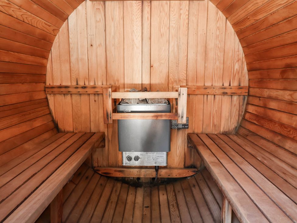A sauna with wooden benches and heating element at The Boat House Rudyard Lake
