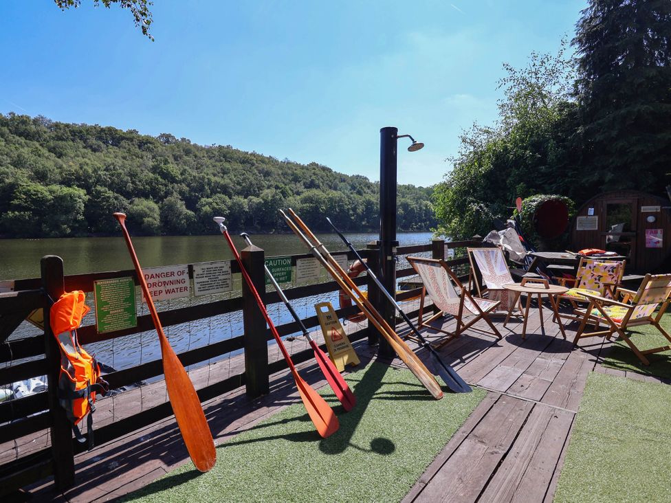 An outdoor area with paddles and chairs by the water at The Boat House Rudyard Lake