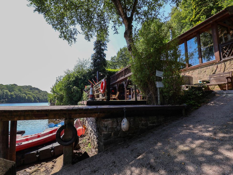 A deck by the water with a lifebuoy and trees at The Boat House in Rudyard Lake