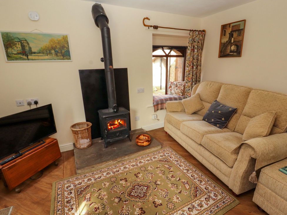 A living room with a sofa and wood stove at The Barn in Warcop