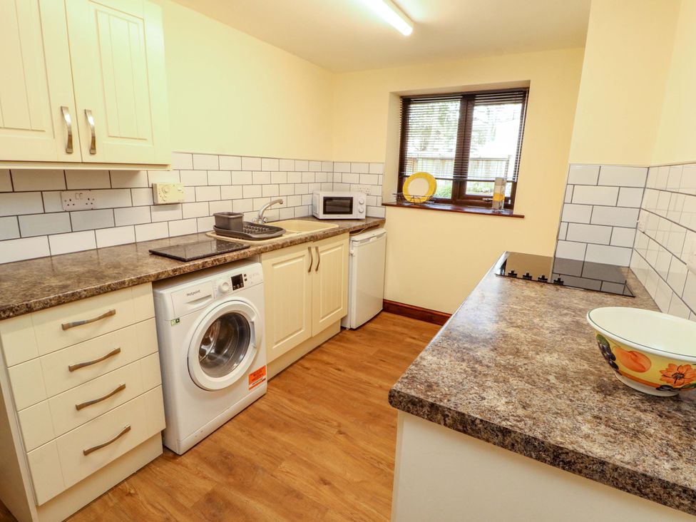 A kitchen with appliances including a washing machine and microwave at The Barn in Warcop