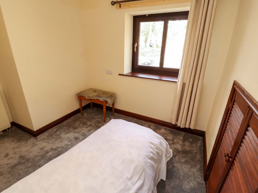 A bedroom with a bed and a bench near a window at The Barn in Warcop