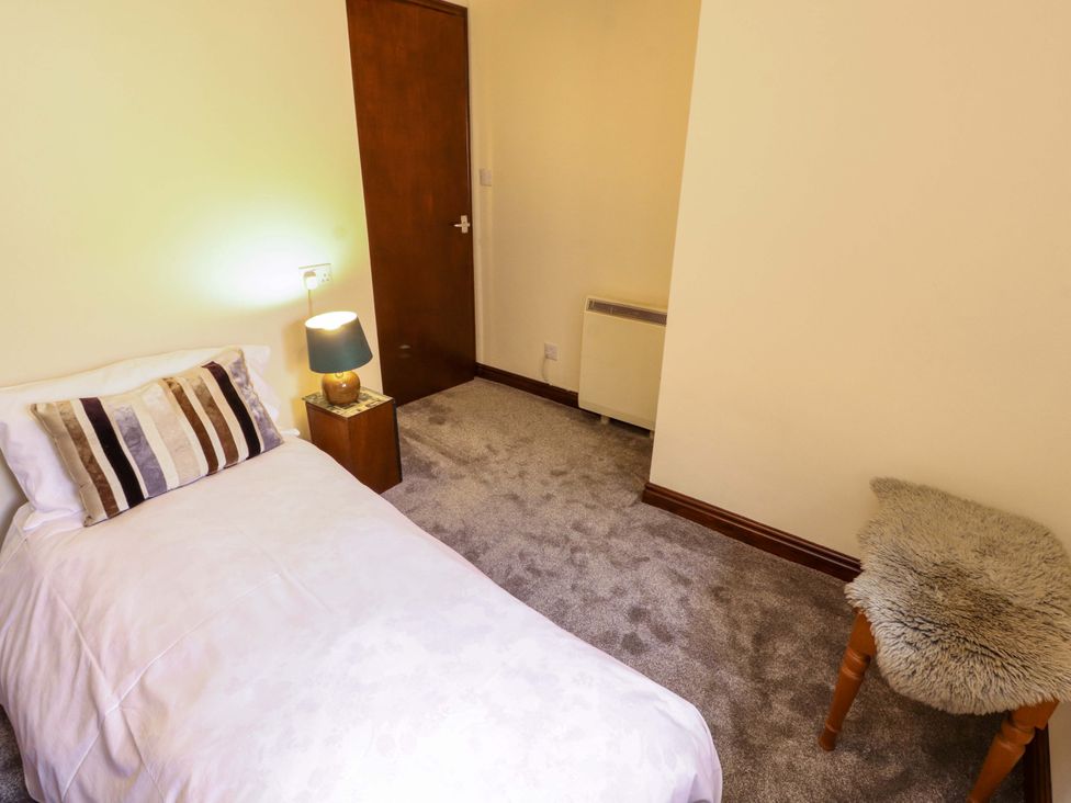 A bedroom with a single bed and a lamp on a nightstand at The Barn in Warcop