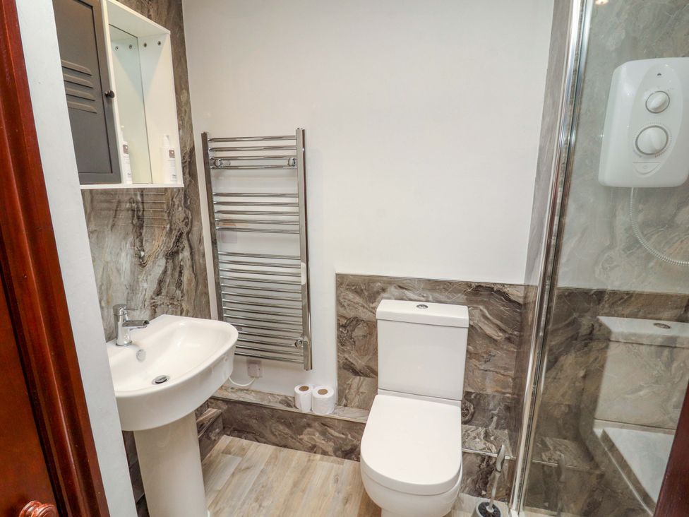 A bathroom with sink, toilet, shower, and towel rail at The Barn in Warcop