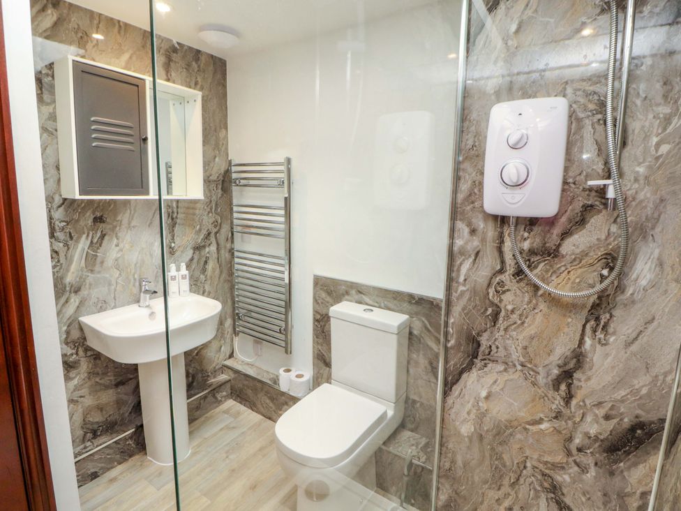 A bathroom with a sink, shower, toilet, and towel rail at The Barn in Warcop