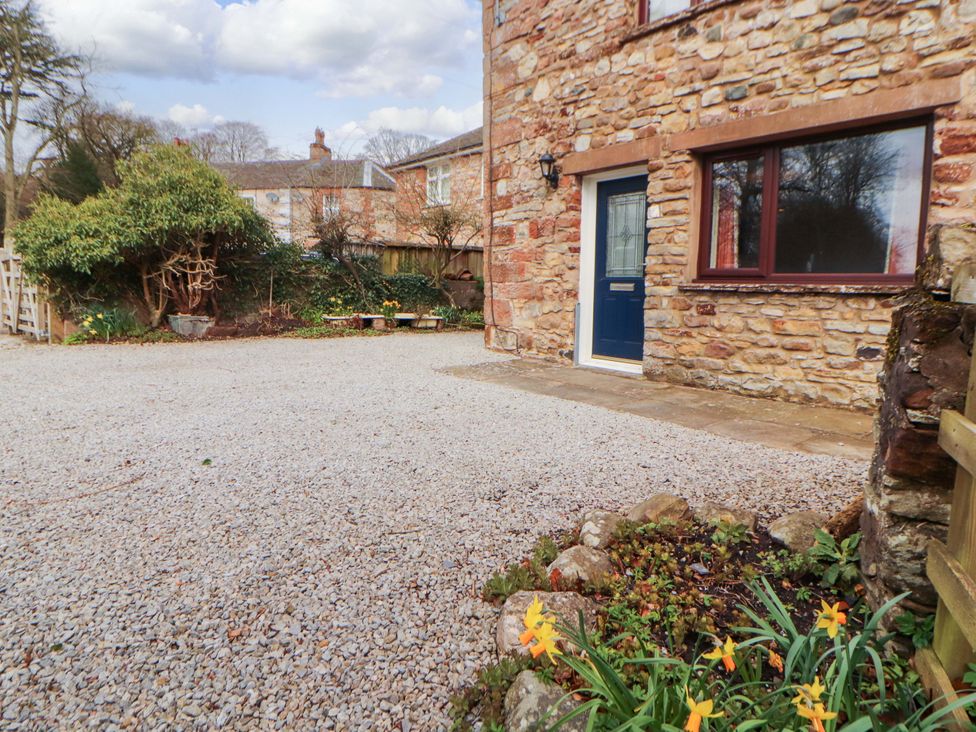 A garden with gravel, stone wall, and plants at The Barn in Warcop