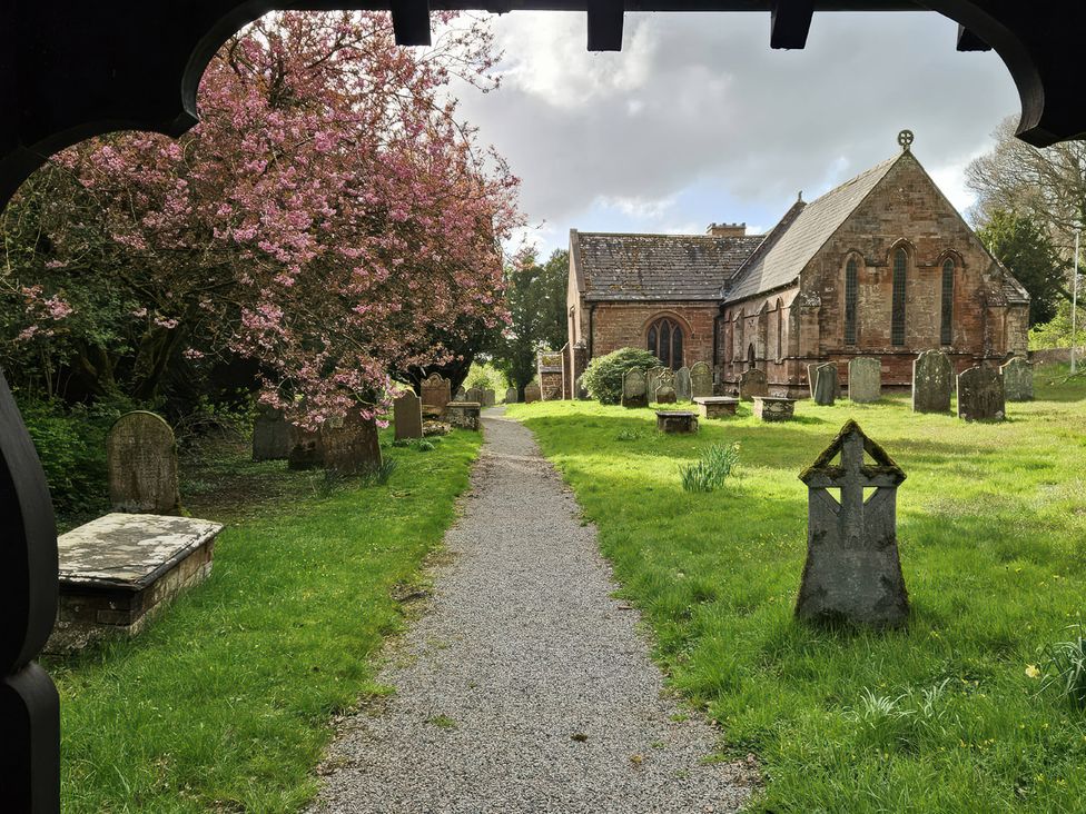 A church with graves and a pathway at Burn Bank in Warcop