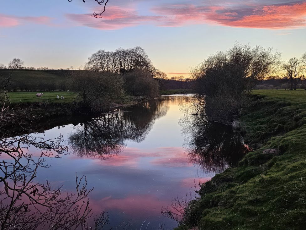 A river with reflection of the sky and cows grazing at Burn Bank in Warcop