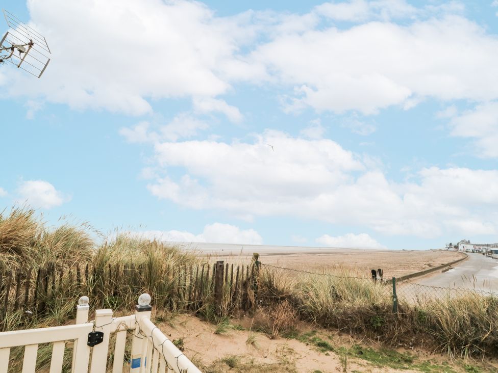 A view of sand and sea with grass and a fence at 37 Redcar