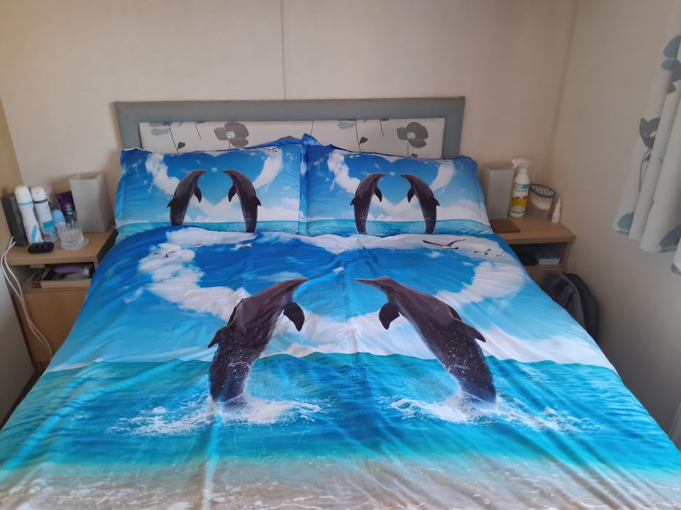 A bedroom with a bed covered in dolphin-themed bedding at Sands Retreat in Redcar