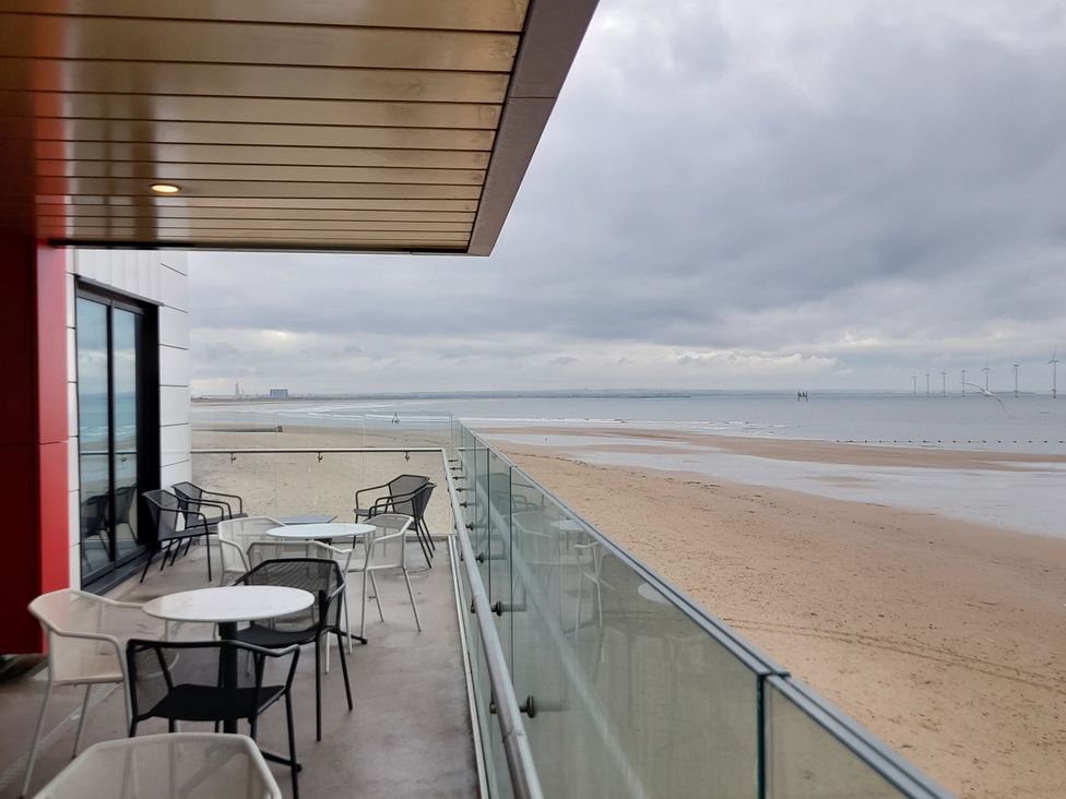 A balcony with tables and chairs overlooking the beach at Sands Retreat in Redcar