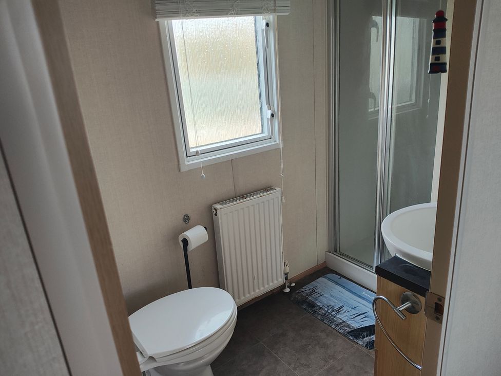 A bathroom with a toilet, shower, washbasin, and radiator at Sands Retreat in Redcar