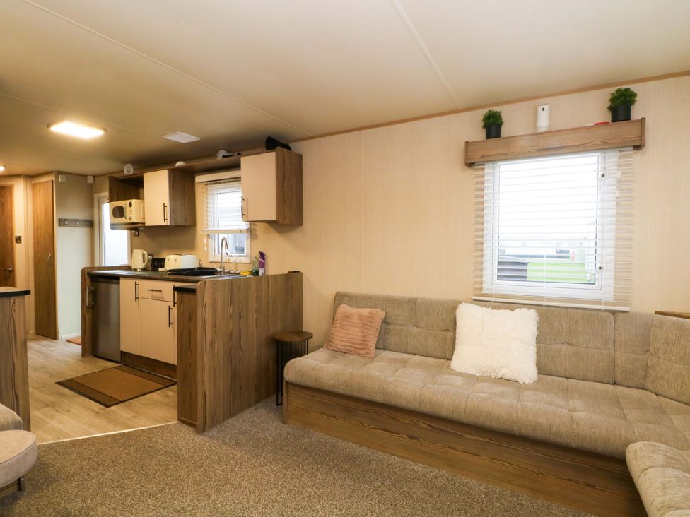 A living room with kitchen units and a sofa at F2