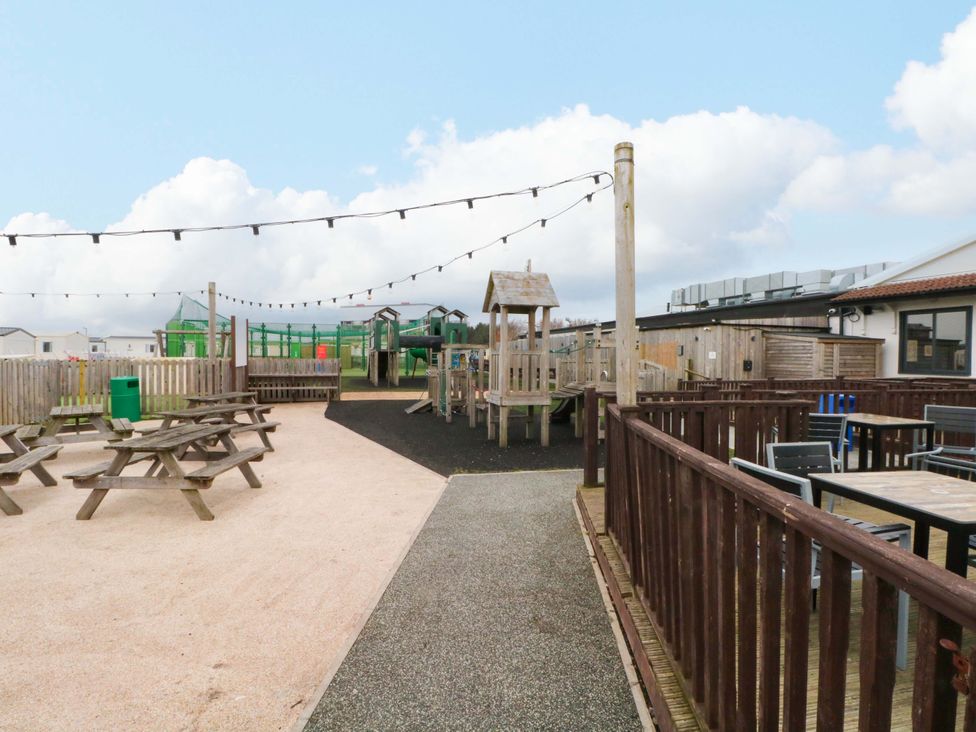 An outdoor play area with playground equipment and picnic tables at F2