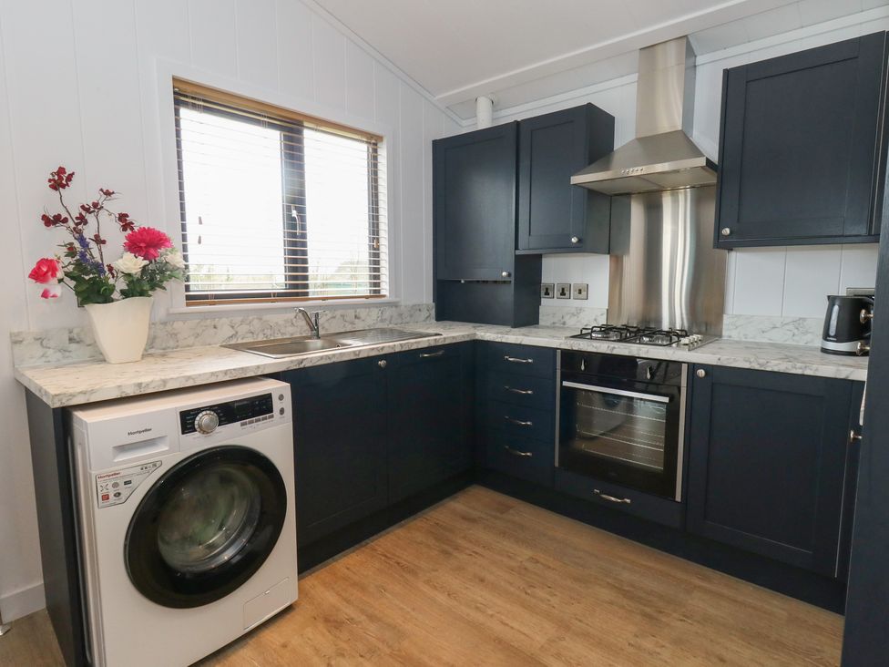A kitchen with a washing machine, sink, and oven at Grass Roots